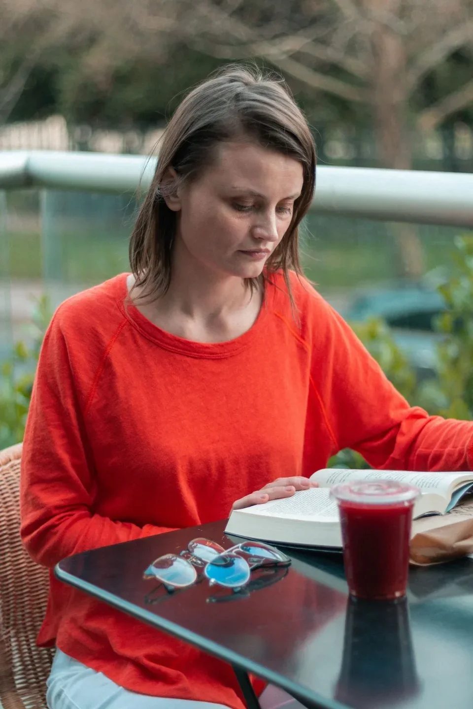 Georgia Blidar leyendo un libro abierto en una mesa de terraza