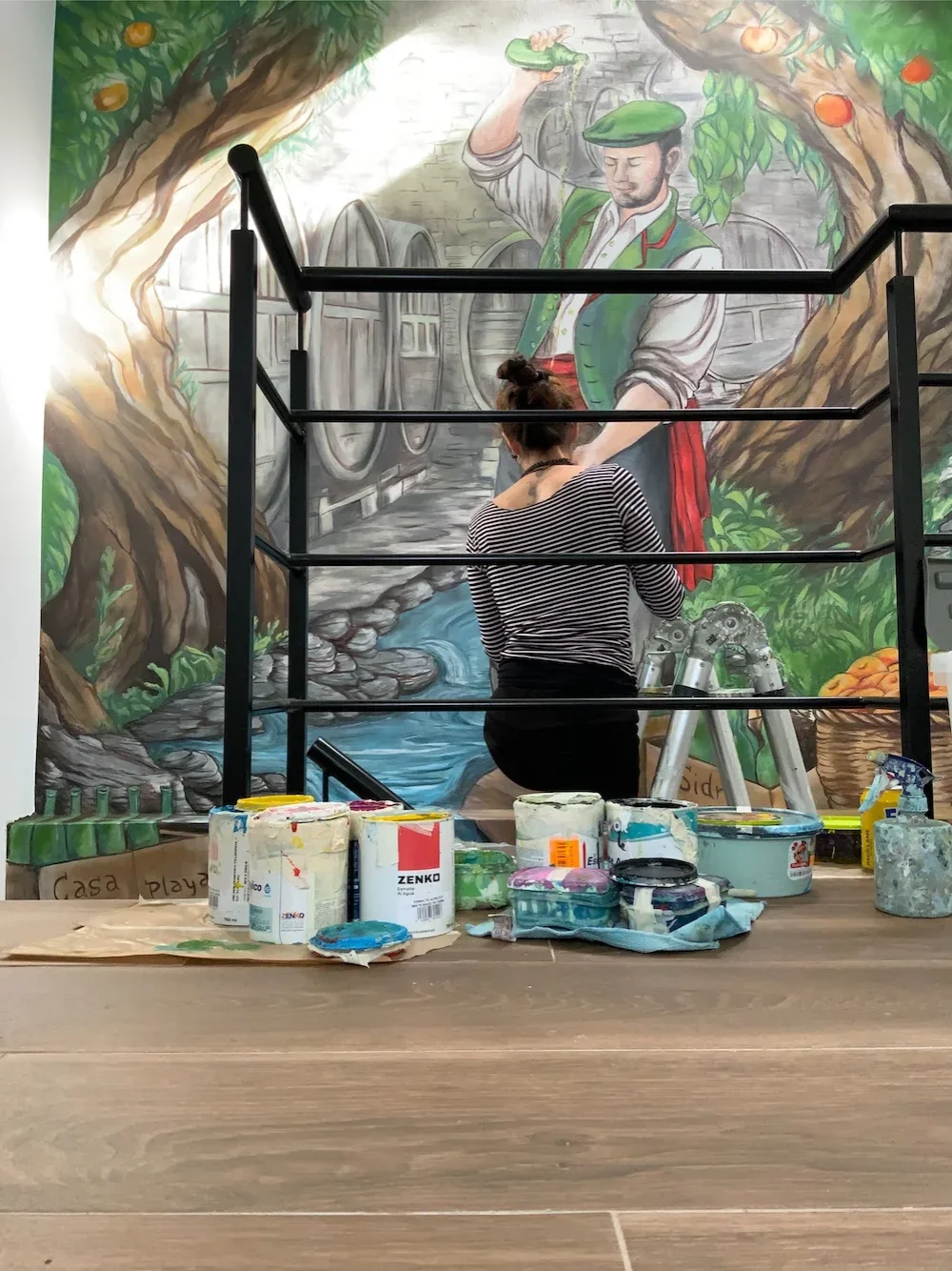 Diana pintando un mural de sidrería con motivo de manzano